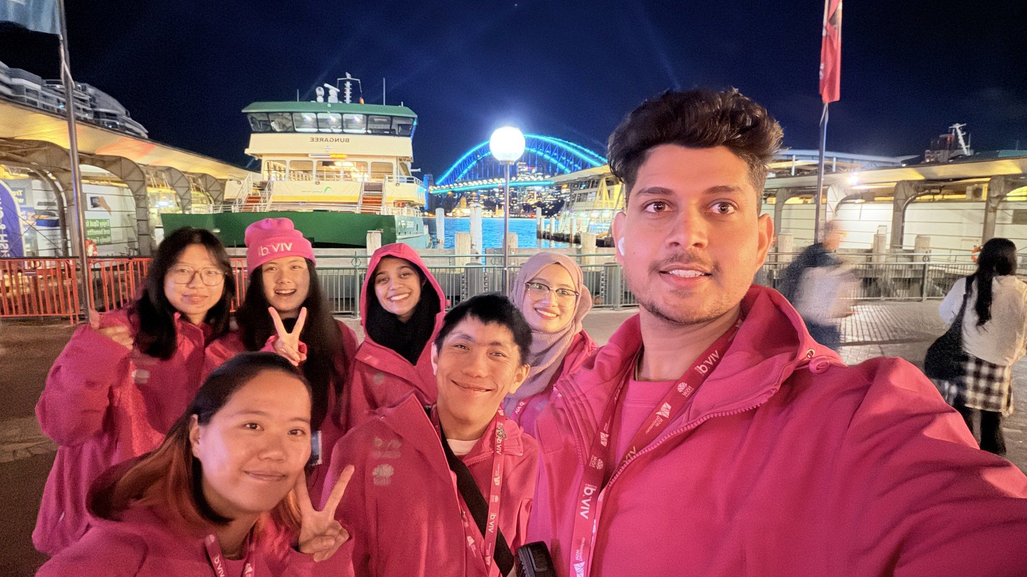 Vivid Sydney volunteer team in pink jackets at Circular Quay at night.